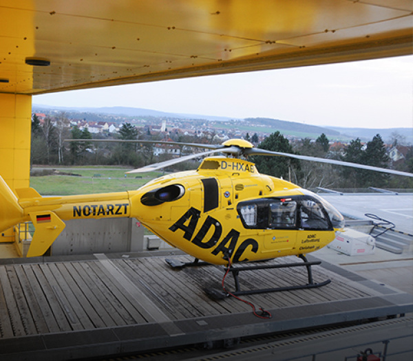 Gelber Rettungshubschrauber der ADAC Luftrettung mit Notarzt-Schriftzug auf Krankenhaus-Heliport.