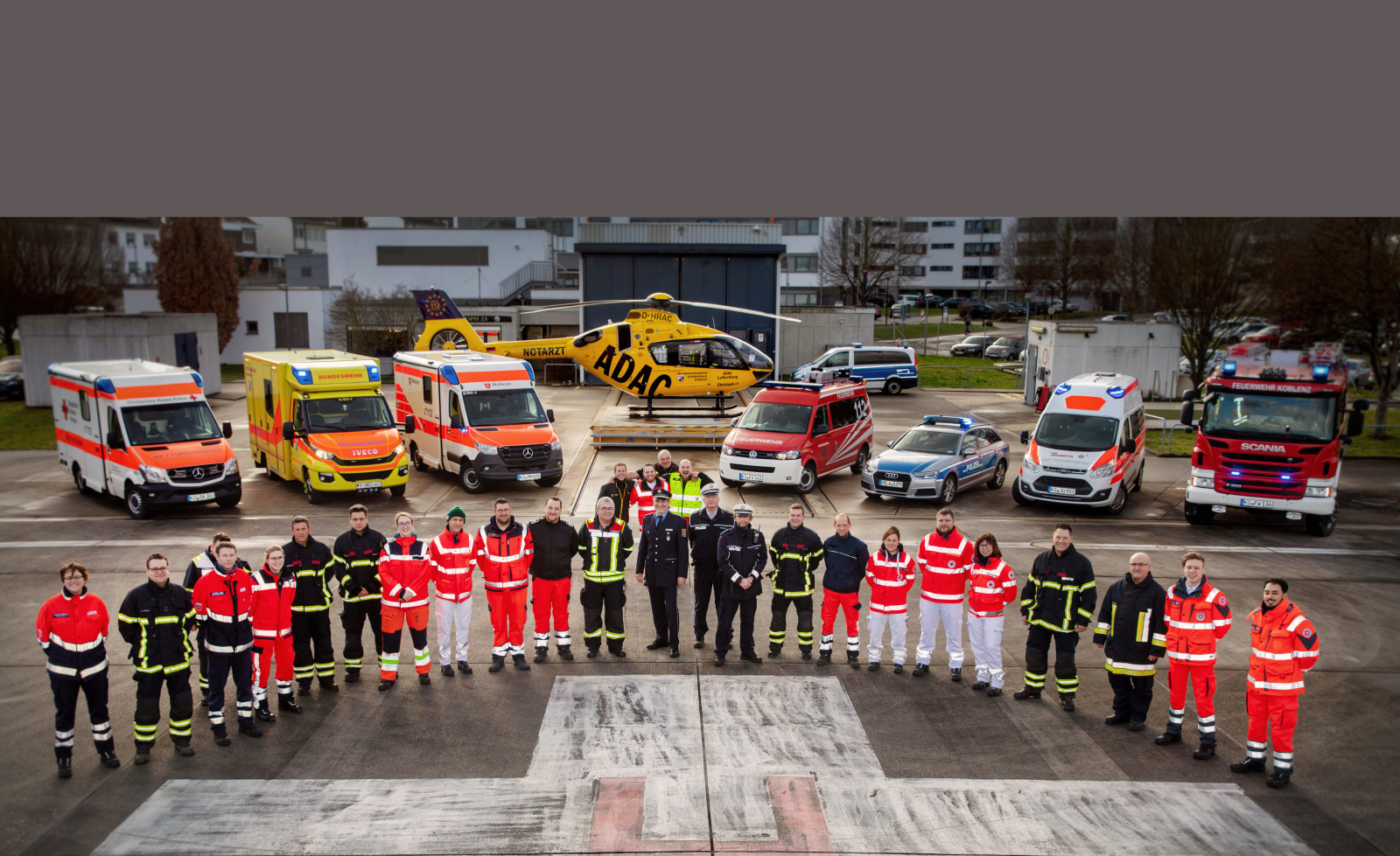 Rettungskräfte vor Rettungsfahrzeugen und Rettungshubschrauber der ADAC Luftrettung