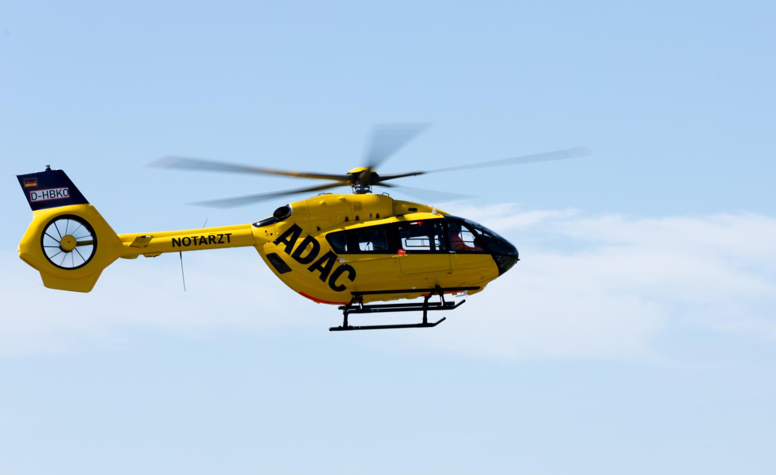 Gelber Rettungshubschrauber der ADAC Luftrettung mit NOTARZT‑Schriftzug im Flug.